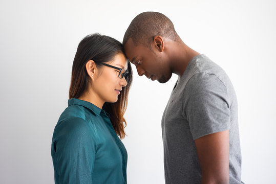 Romantic Multiracial Couple Touching Their Foreheads. Portrait Of Young Afro American Man In Love And His Asian Girlfriend With Closed Eyes. Love And Romance Concept