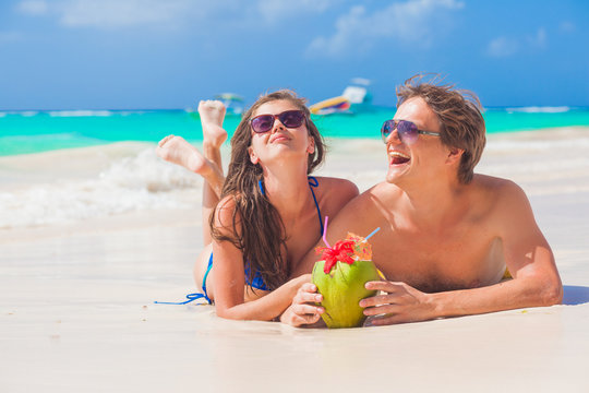 couple lyind and drinking a coconut cocktail on a tropical beach in Barbados