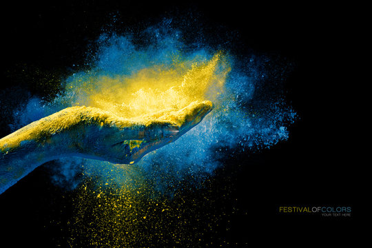Hand holding yellow holi powder over an explosion of color