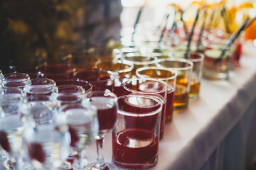 Beautiful row line of different colored alcohol cocktails on a party,  on decorated catering bouquet table
