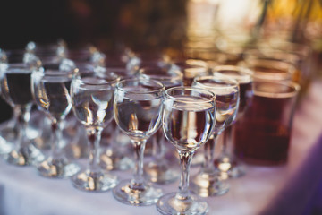 Beautiful row line of different colored alcohol cocktails on a party,  on decorated catering bouquet table
