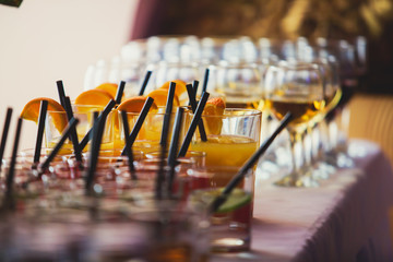 Beautiful row line of different colored alcohol cocktails on a party on decorated catering banquet table
