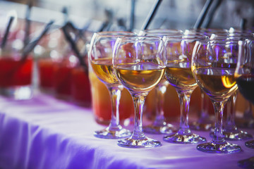 Beautiful row line of different colored alcohol cocktails on a party on decorated catering banquet table
