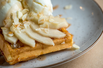 Wonderful breakfast or dessert - vanilla ice cream with caramel sauce on Belgian waffle with slices of ripe pear, top view