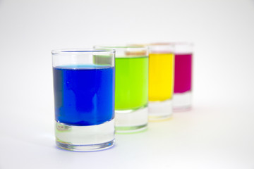 Multicolored glasses of different drinks. Party and holiday celebration concept. Four glasses with a blue, green, yellow and red drink. Isolated on white background.