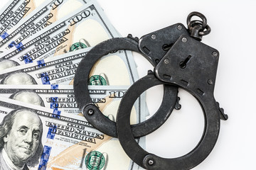 black metal handcuffs lie on 100 dollar bills