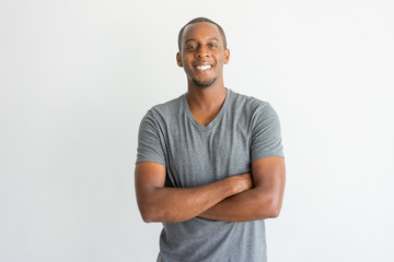 Happy excited young African man crossing arms on chest and looking at camera. Optimistic confident handsome guy in t-shirt smiling. Joy concept