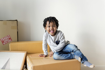 Young cheerful black boy moving to new house - obrazy, fototapety, plakaty