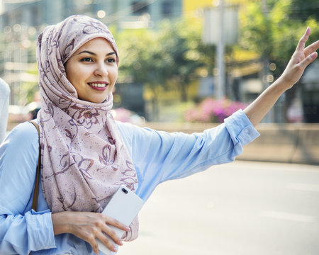 Islamic woman calling taxi in the city - Powered by Adobe