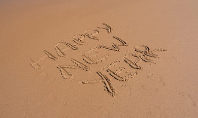 Happy new year written on sand at sunset. Happy New Year lettering on the beach. 