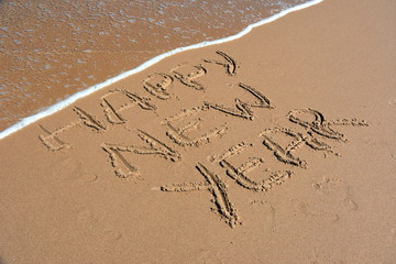 Happy new year written on sand at sunset. Happy New Year lettering on the beach. 
