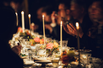People enjoy a family dinner with candles. Big table served with food and beverages. - 201292957