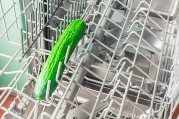 Long green cucumber lies in the middle compartment of the dishwasher