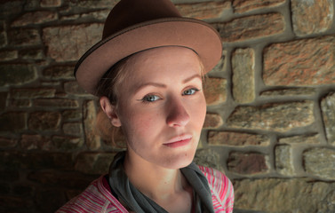 portrait of a young caucasian female hiker wearing a hat standing in a stone hiking shelter