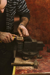 Man works in carpentry workshop. He cuts slit for wedge in a wooden handle with knife. Men at work. Manual labor.