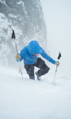 female hiker walking in a bad weather in winter alpine mountains