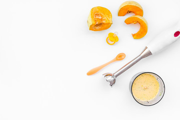 Make baby food at home. Puree with pumpkin near immersion blender and pacifier on white background top view copy space