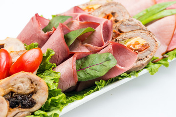 meat rolls with ham, cheese and greens on white background