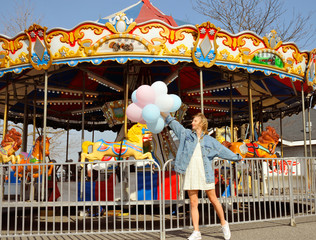 Fototapeta na wymiar Beautiful young woman with balloons in the amusement park