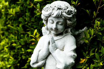 Fototapeta na wymiar Statues of Guardian angels in green garden