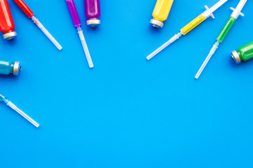 Medical injection. Syringe and bottle with remedy on blue background top view copy space