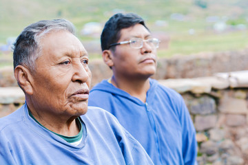 Old serious native american father with his son in the countryside.