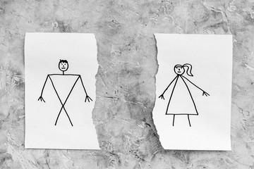 Divorce or falling apart concept. Torn sheet of paper with drawn man and woman on grey background...