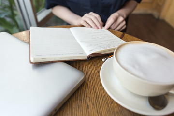 Woman's hands above a notebook.   Coffee cup and laptop for business, Selective focus on notebook.