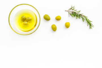 Make olive oil concept. Green olives in bowl with olive oil on white background top view copy space
