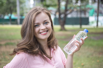 Young caucasian woman holding plastic bottle with water in her hand