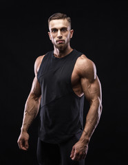 Fototapeta premium Portrait of a muscular male model against black background