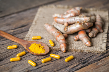 Turmeric powder and turmeric on wooden background