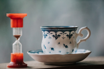 Obraz na płótnie Canvas Elegant tea cup and hourglass stand shelf