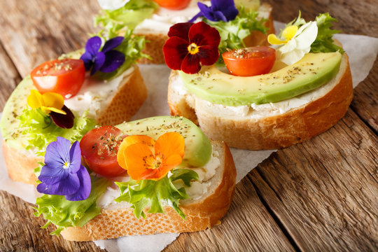 Organic healthy sandwiches with avocado, lettuce, tomatoes, edible flowers and cream cheese close-up. horizontal