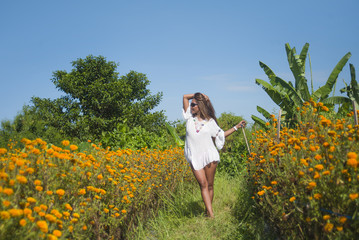 happy and beautiful young Asian woman relaxing enjoying the fresh beauty of gorgeous orange marigold flowers field natural landscape in travel destination