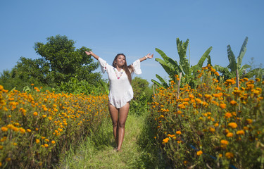 happy and beautiful young Asian woman relaxing enjoying the fresh beauty of gorgeous orange marigold flowers field natural landscape in travel destination