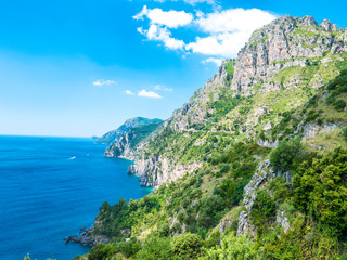 Fototapeta na wymiar Infinite view of the Amalfi Coast with wild coastline, perfectly preserved environment, vertical rocky cliffs, luxuriant green forest and blue coves of the Mediterranean sea. - Amalfi, Naples, Italy