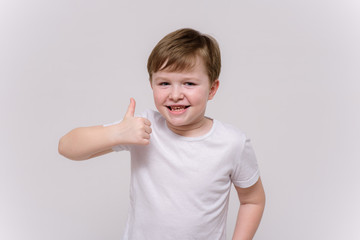 cute boy aged 6 years shows on a white background in different poses different emotions