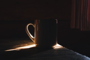 cup of coffee in a morning light, rustic wooden cottage interior