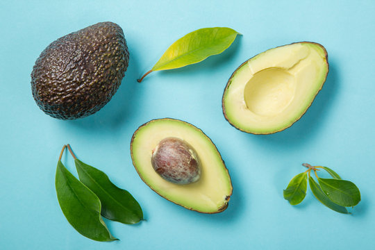 Slices of avocado on bright background. Whole and half with leaves. Design element for product label