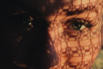 portrait of a woman standing next to a window, sunset through curtain cast a shadow on her face