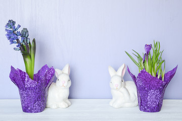 Ceramic bunnies, potted hyacinth and  crocus on a white wood surface with a lilac backdrop with plenty of copy space for your Easter or spring message