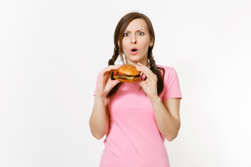 Young beautiful woman in pink t-shirt with braids holding in hands burger isolated on white background. Proper nutrition or American classic fast food. Copy space for advertisement. Advertising area.