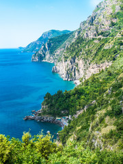 Fototapeta na wymiar Infinite view of the Amalfi Coast with wild coastline, perfectly preserved environment, vertical rocky cliffs, luxuriant green forest and blue coves of the Mediterranean sea. - Amalfi, Naples, Italy