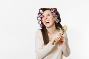 Young woman with curlers using combing with comb her hair isolated on white background. Crazy...
