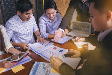 Business people meet to discuss the situation of marketing in the office and have information sheets on the table.