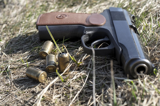 Makarov pistol with bullets on the old grass background