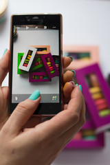 photo in the phone of macaroons in colored boxes