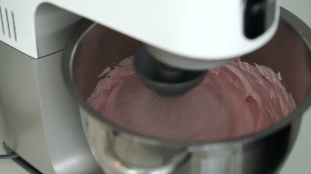 The steel whisk of an electric mixer whipped up a burgundy confectionery mass in a bowl for cooking a natural strawberry marshmallow.Homemade sweet. Homemade marshmallow dessert. Selective focus.