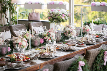 Garland of flowers and greenery for table decoration. Luxury wedding reception in restaurant. Stylish decor and adorning. Tables served with beautiful dishes and delicious food